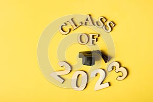 Class 2023 concept. Wooden number 2023 with graduated cap on yellow background