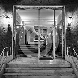 A classic 60s luxury residential apartments building entrance night capture in black and white.
