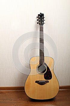 Acoustic guitar stands against the wall