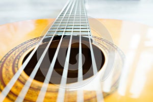 Classic acoustic guitar at weird and unusual perspective closeup. Six strings, free frets, sound hole and soundboard.