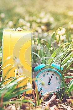 Classic alarm clock with bells on nature background. Daylight saving time reminder. Spring time change background