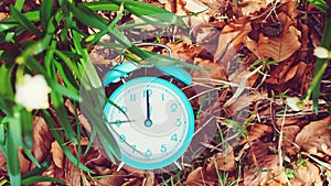 Classic alarm clock at nature background, top view. Daylight saving time reminder. Spring time change background