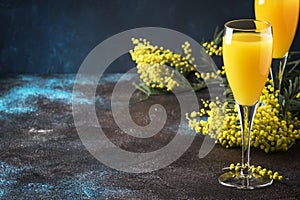 Classic alcohol cocktail mimosa with orange juice and cold dry champagne or sparkling wine in glasses, blue stone background with