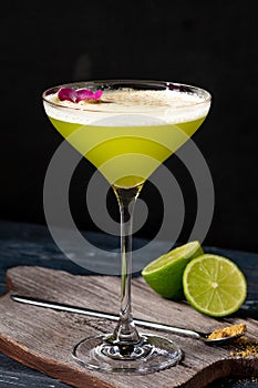 Classic alcoholic cocktail Daiquiri with lime and kiwi in a glass on a black background