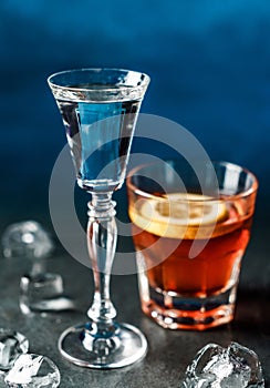 Classic alcoholic cocktails in shot glasses or shooters on dark blue background. Drink and beverages