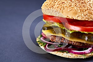 Classic American cheeseburger with black flag on the top over dark background, close-up, selective focus