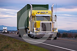 Classic American powerful yellow semi truck with chrome tailpipe