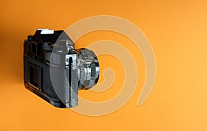 Classic analog slr camera from the era of film photography on orange background