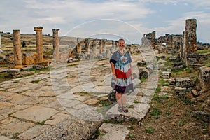 A classic antique Greek theater in Pamukkale, Denizli, Turkey and a white young woman in a hippie dress