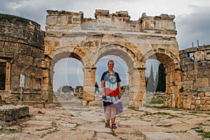 A classic antique Greek theater in Pamukkale, Denizli, Turkey and a white young woman in a hippie dress