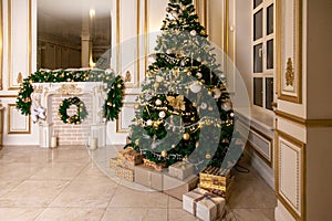 Classic apartments hall with a white fireplace, decorated christmas tree with gift boxes, large mirror and windows