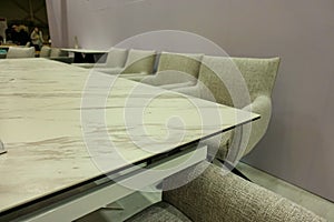 Classic armchairs upholstered in gray fabric stand behind a long table photo