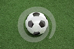 Classic ball for playing soccer in white with black accents on artificial turf, close-up view