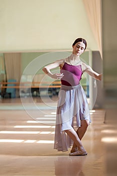 Classic ballet dancer posing at barre on rehearsal