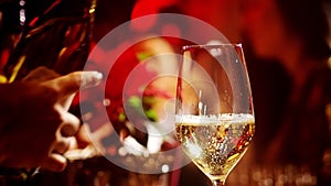 A classic bartender pours sparkling wine from a tall glass into a cocktail glass in the interior of a stylish bar.