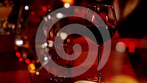 A classic bartender pours sparkling wine from a tall glass into a cocktail glass in the interior of a stylish bar.