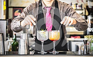 Classic bartender serving gin tonic and tequila sunrise cocktails at bar