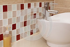 Classic bathroom sink with coloured mosaic splashback