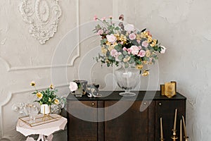 Classic bedroom interior. A brown wooden chest of drawers, flowers in a glass vase, and a white bedside table