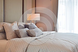 Classic bedroom interior with pillows and reading lamp on bedside table