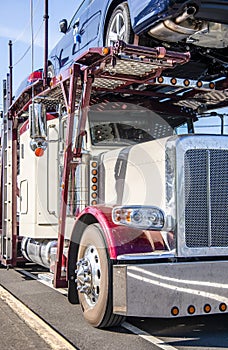 Classic big rig car hauler semi truck standing on the road for unloading delivered cars