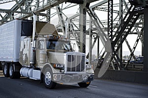 Classic big rig semi truck with refrigeration unit on reefer semi trailer running on the Interstate bridge