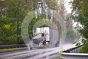 Classic Big rig truck in raining weather wet road