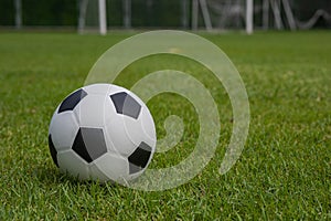 Classic black and white football placed on a grass pitch.