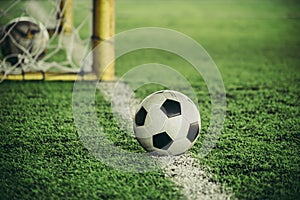 Classic black white football soccer ball on training pitch goal line with goal in the background