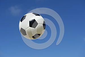 Classic Black and White Soccer Ball Football Flying in Blue Sky