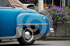 Classic blue car parked in front of flower basket