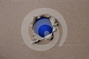 Classic Blue empty blank cardboard form, craft paper, hole with roughly torn edge, concept of secrecy, tracking, spying, blank for