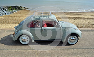 Classic Blue Grey Volkswagen Beetle Motor Car Parked on Seafront Promenade.