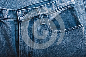 Classic blue jeans background. Denim texture fabric with a seam of fashionable design. Empty pattern copy space. Selective focus