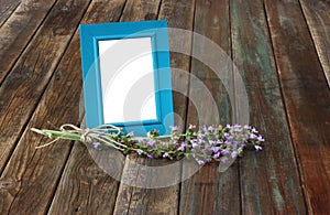 Classic blue picture frame on wooden table and sage plant decoration.