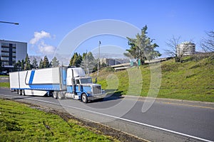 Classic bonnet American big rig semi truck transporting frozen cargo in refrigerator semi trailer running on highway exit road