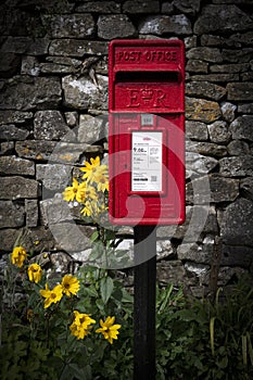 Classic British letterbox in rural setting with flowers
