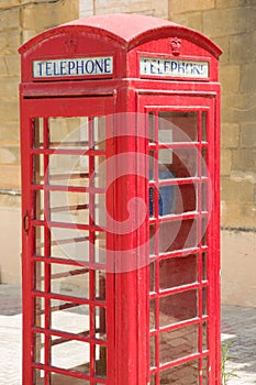 Classic British style of red, wooden telephone-box with blue phone inside