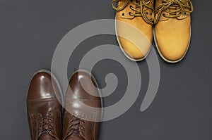 Classic brown leather men`s shoes and Yellow men`s work boots from natural nubuck on gray black background top view flat lay cop