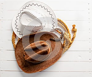 brown and white cowboy hat lasso and horseshoe wild west still life on rough white wooden table