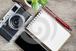 Classic camera with blank notepad page and red pen on gray wooden, vintage desk with telephone