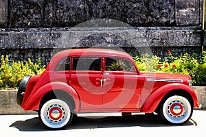 Classic car with bright red color parked in front of old building in Solo, Central Java, Indonesia