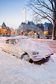 Classic car covered with snow on a winter day during sunset in Amsterdam