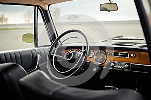 Classic car interior with black leather, wood and chrome trim