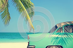 Classic car on a tropical beach with palm tree