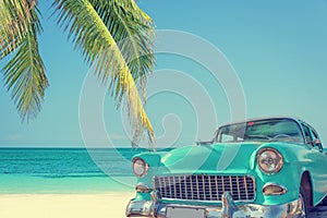 Classic car on a tropical beach with palm tree, vintage process