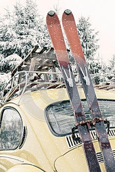 Classic car with vintage ski`s and sled during snowfall