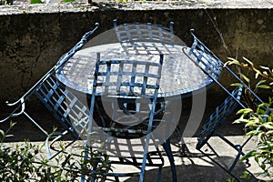 Classic chairs and iron table on a sunny terrace. Very nice blue color for these garden furniture. Summer background.