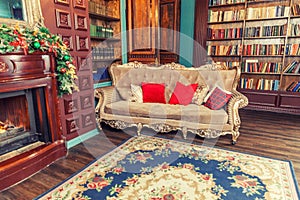 Classic Christmas New Year decorated interior room home library with fireplace. Christmas tree with red ornament decorations.