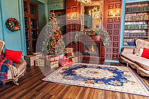 Classic Christmas New Year decorated interior room home library with fireplace. Christmas tree with red ornament decorations.